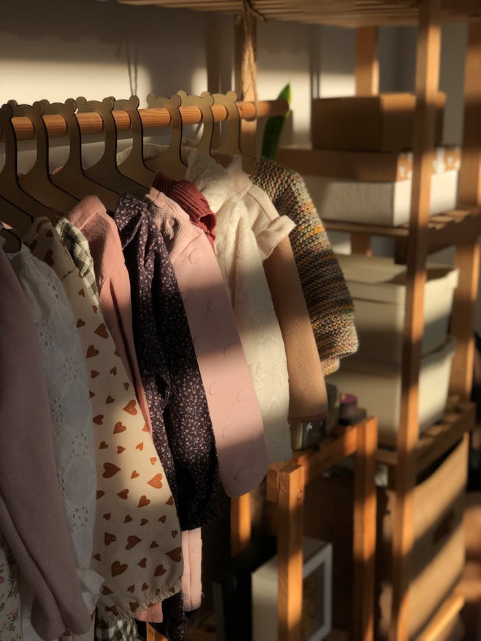 creative-01 A selection of children's clothes hanging on wooden hangers in warm sunlight.